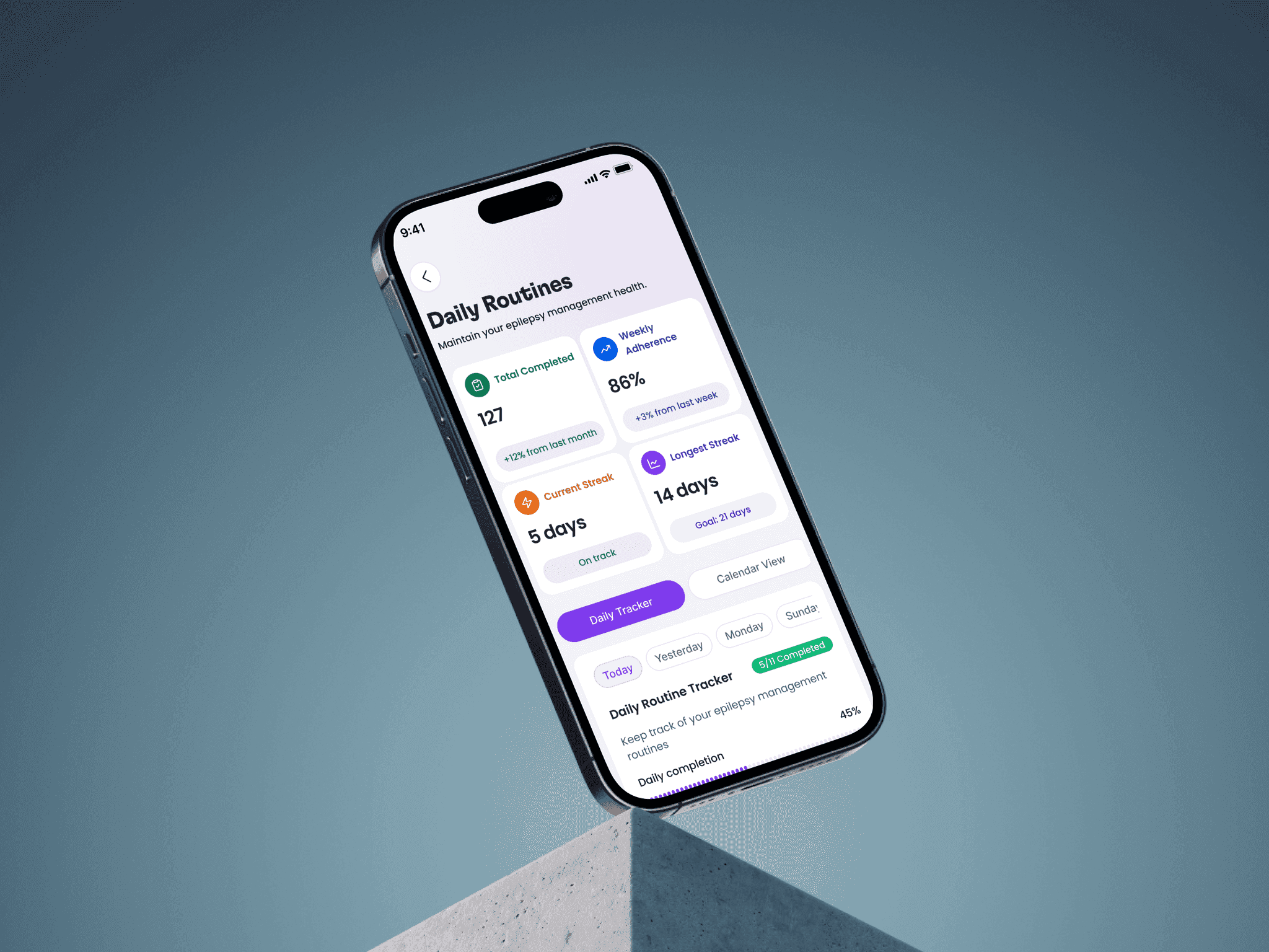 A phone floating above a concrete block showing the Daily Routines screen: 127 total completed, 86% weekly adherence, a 5-day current streak, a 14-day longest streak with a 21-day goal, and a daily routine tracker at 45% completion.